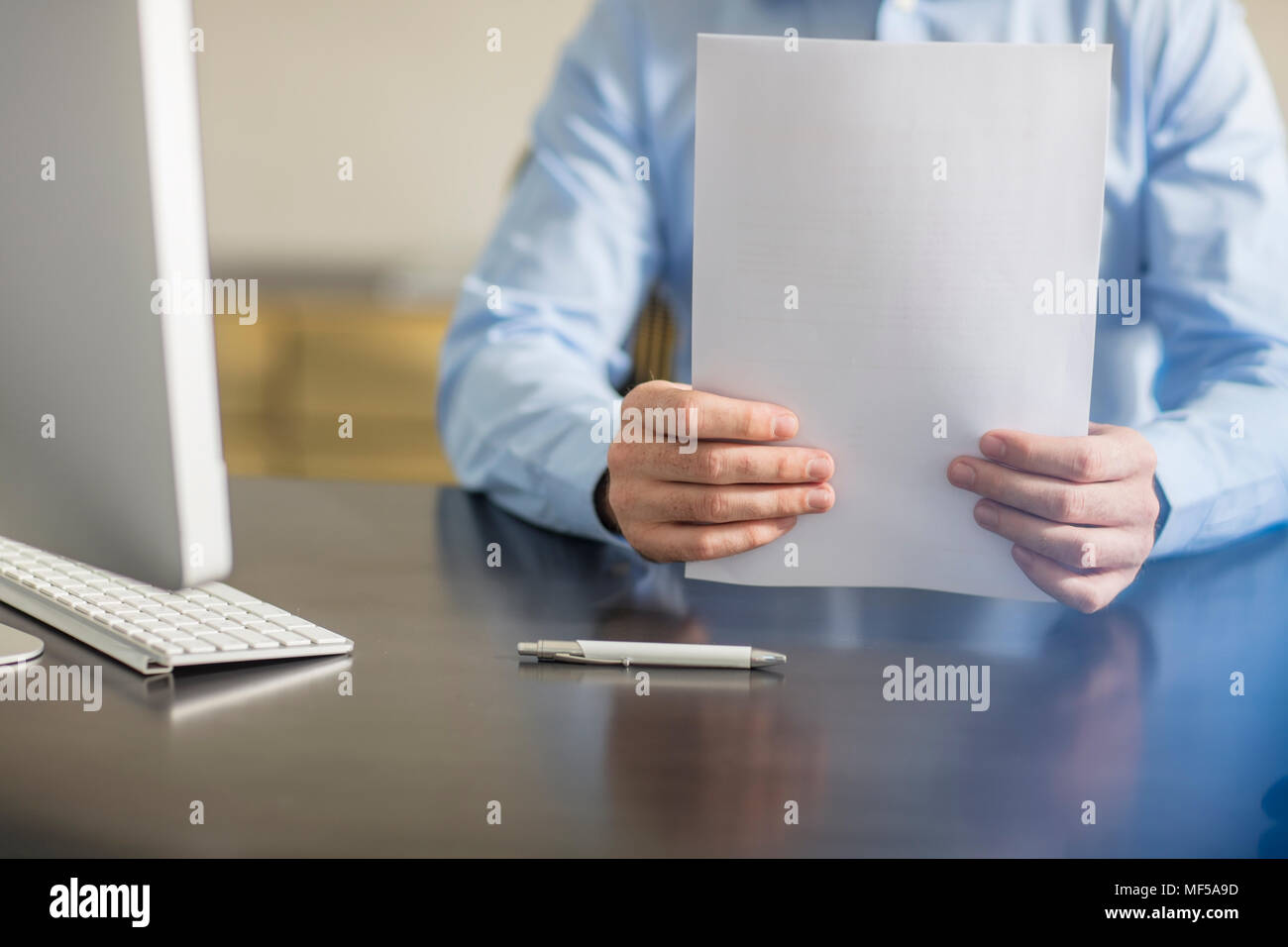 Businessman sitting at office desk avec stylo-bille et documents Banque D'Images