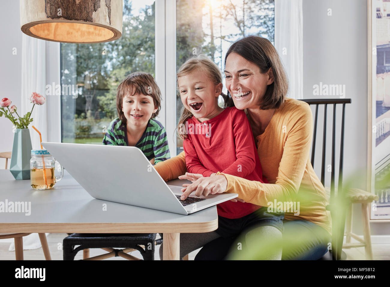 Heureuse mère de deux enfants à l'aide d'ordinateur portable à la maison Banque D'Images