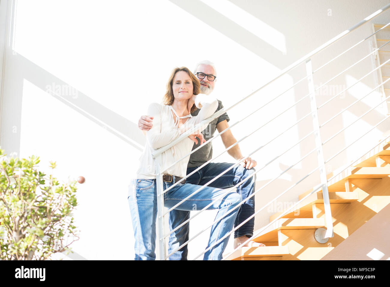 Portrait of smiling mature couple debout dans les escaliers à la maison Banque D'Images Portrait of smiling mature couple debout dans les escaliers à la maison Banque D'Images