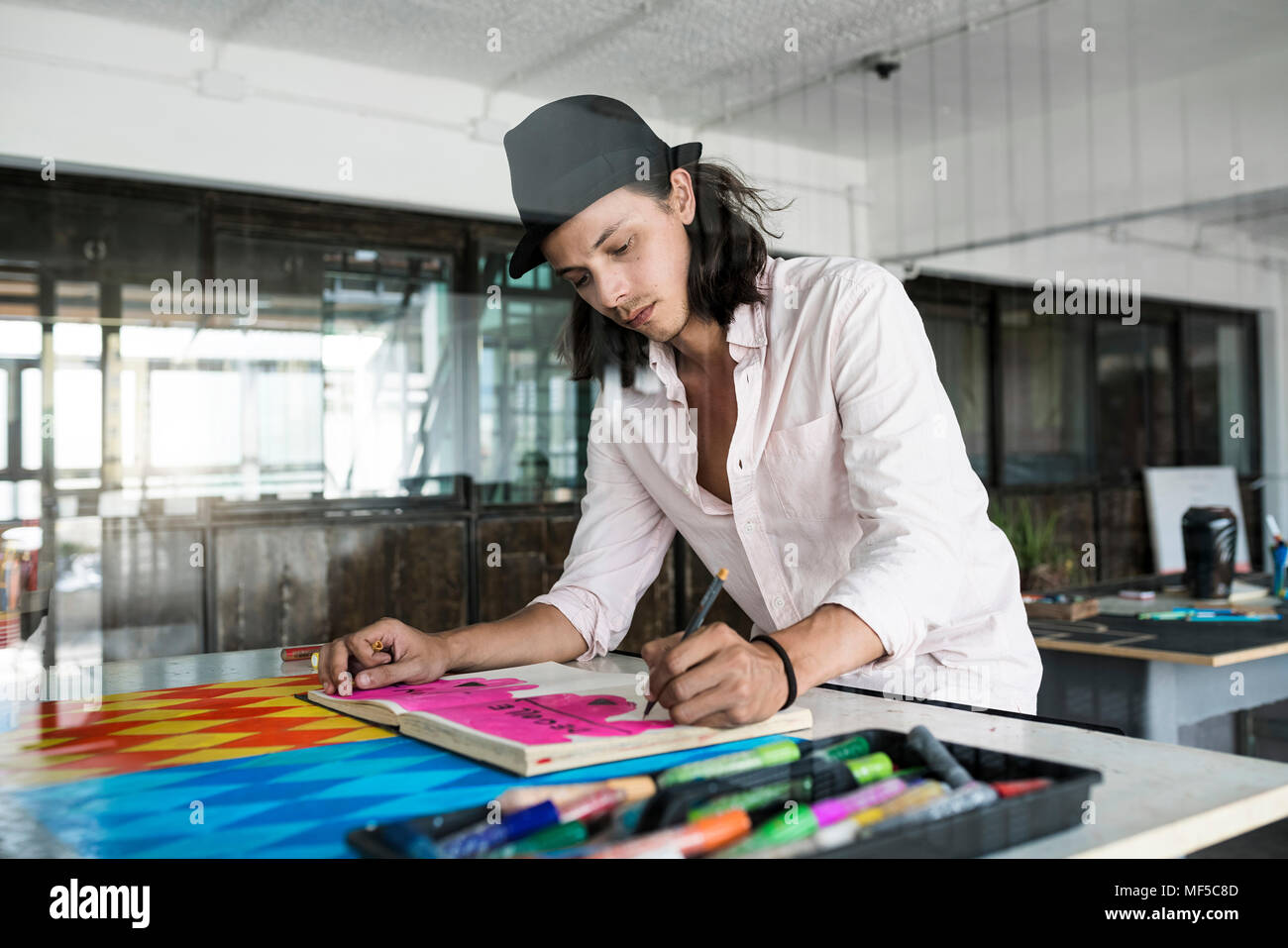 Artiste au travail, des dessins d'un ordinateur portable dans son studio loft Banque D'Images