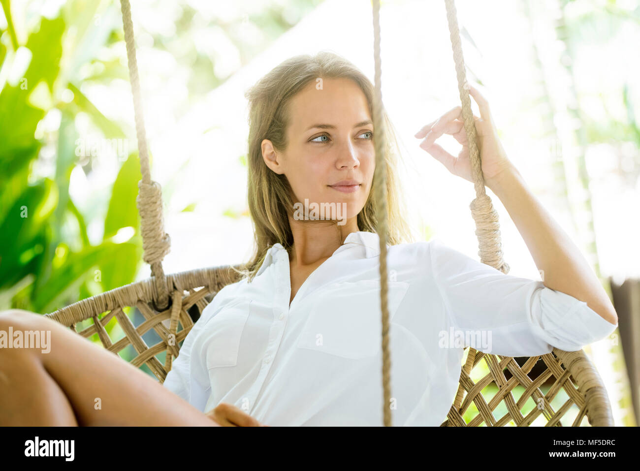 Smiling woman relaxing in fauteuil suspendu Banque D'Images