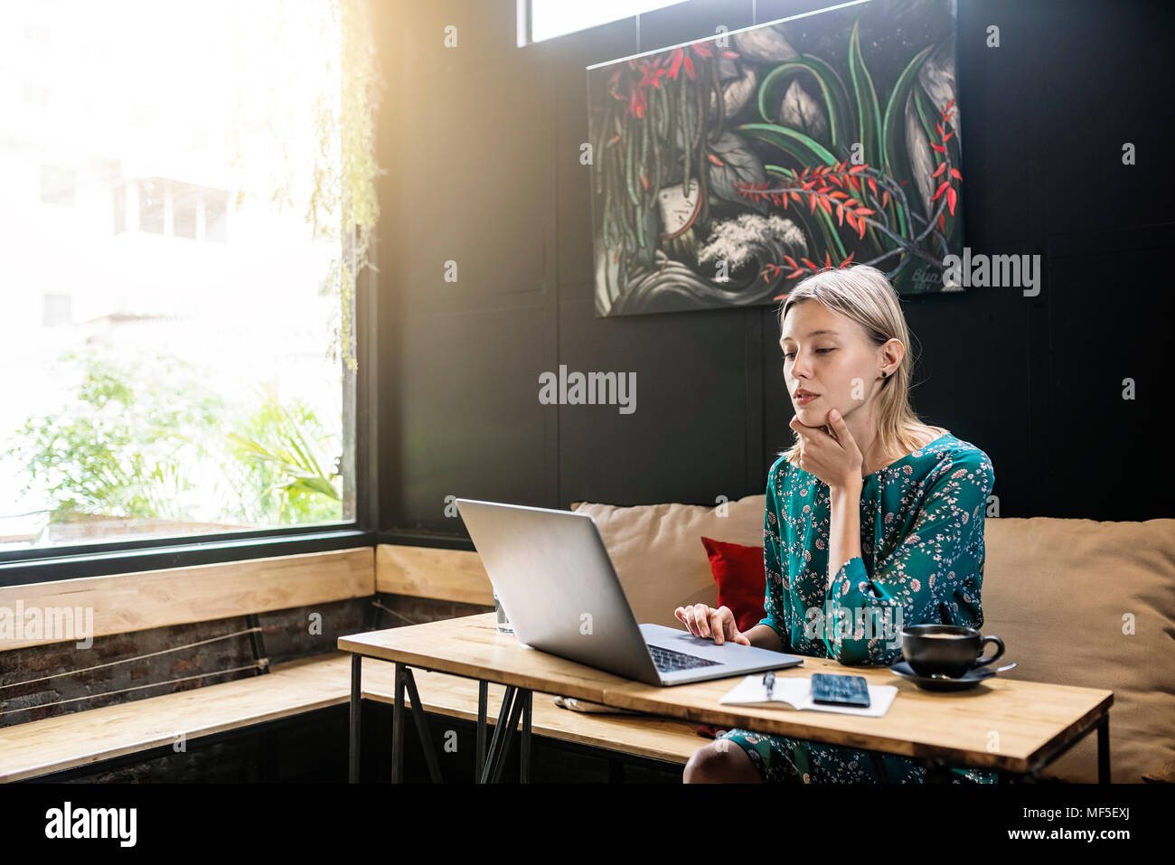 Jeune femme avec robe vert assis dans cafe , travailler sur son ordinateur portable Banque D'Images