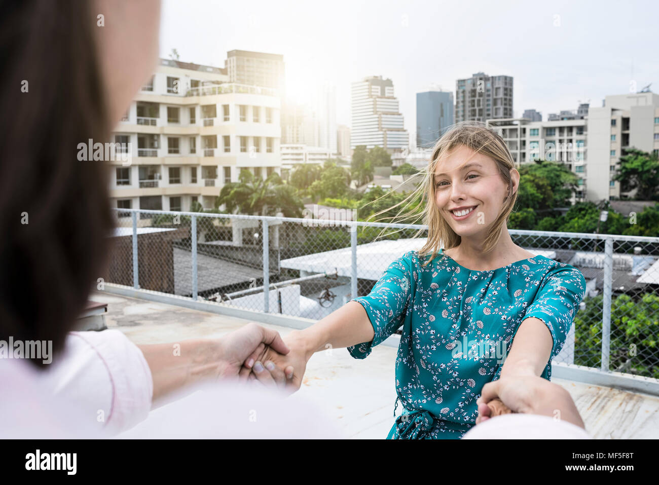 Young woman holding hands with boyfriend on rooftop Banque D'Images