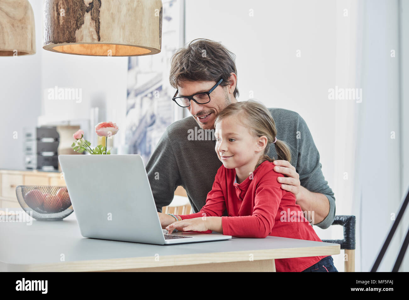 Smiling père et fille à l'aide de l'ordinateur portable sur le tableau à la maison Banque D'Images