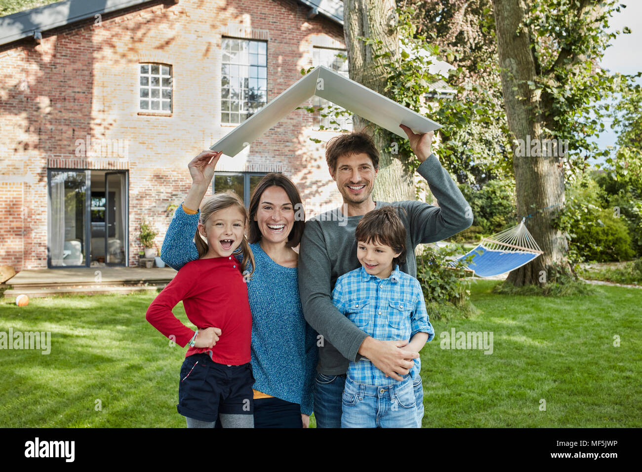 Portrait de famille heureuse dans le jardin de leur pavillon accueil holding Banque D'Images