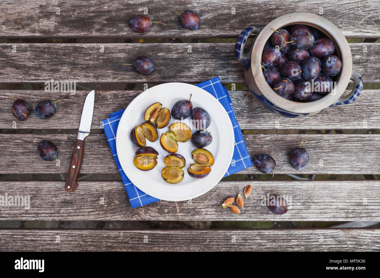 Les prunes fraîches en pot grès et prunes hachées sur la plaque Banque D'Images