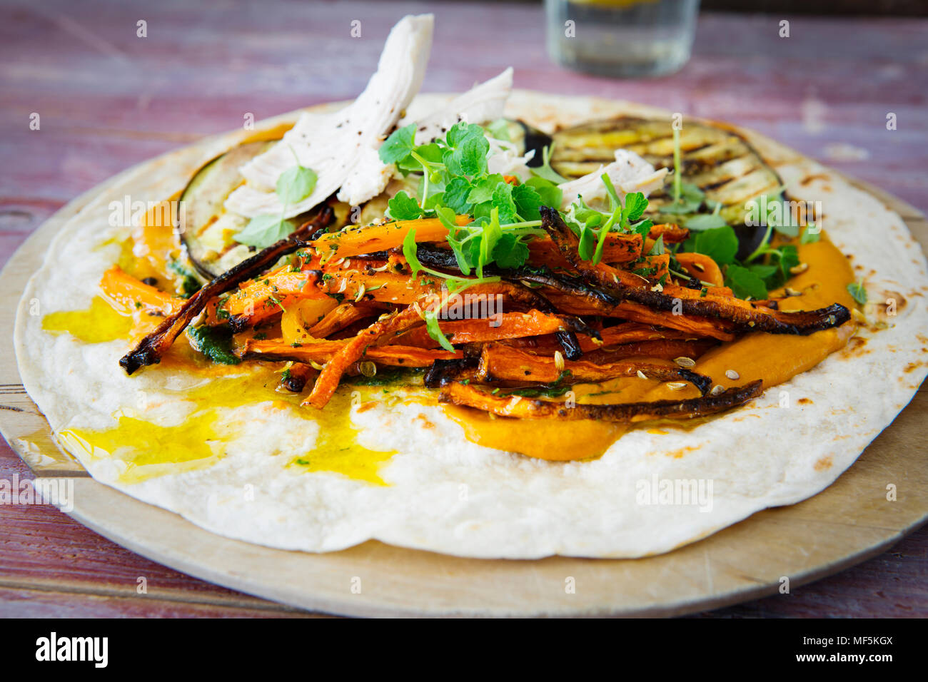 Tiré roulé au poulet, carotte, aubergine grillée, curry, herbes de l'hoummos sur planche à découper Banque D'Images