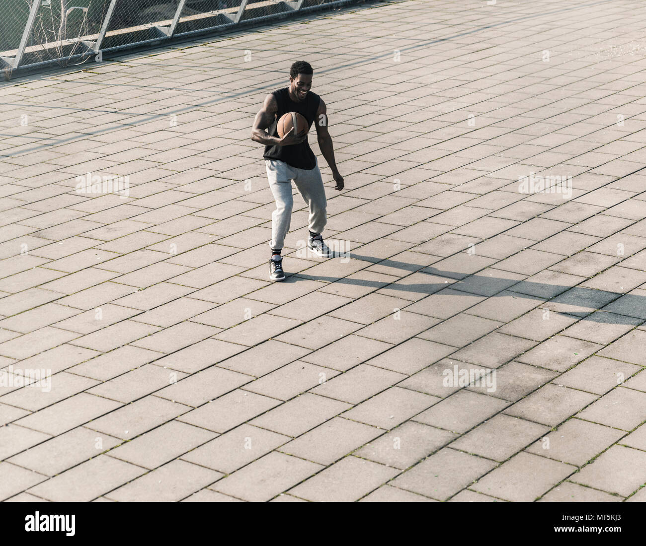 Joueur de basket-ball de rire en action sur un carré Banque D'Images