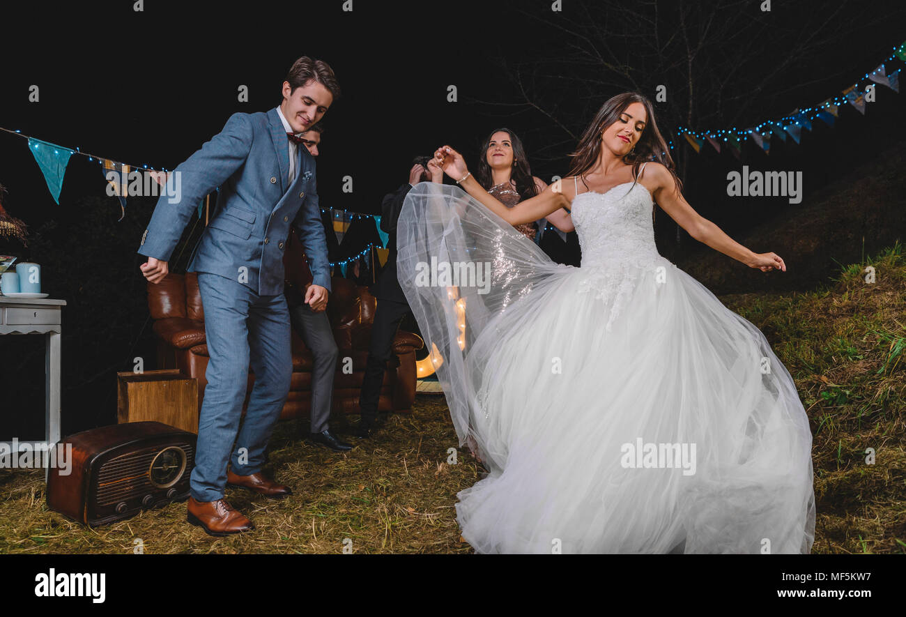 Happy bride la danse et avoir du plaisir avec ses amis sur un champ de travail de nuit Banque D'Images