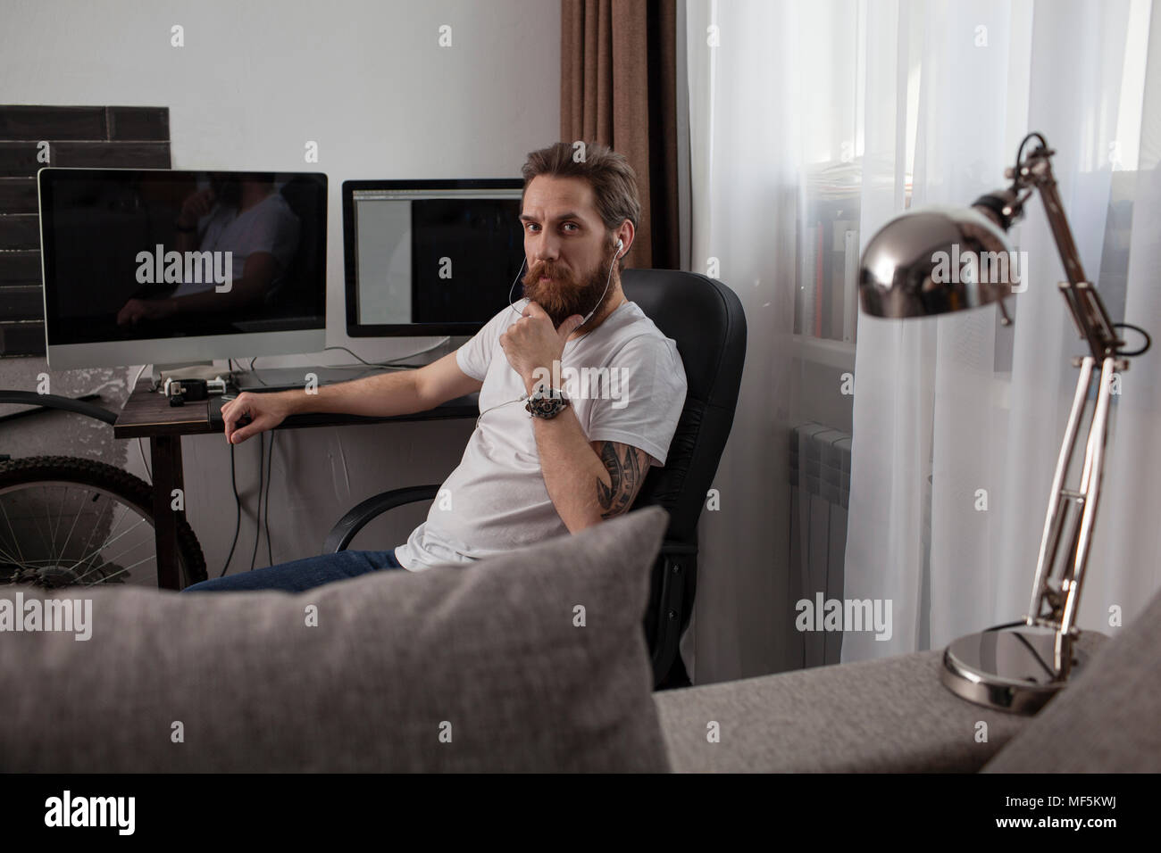 Portrait d'homme barbu assis dans le salon d'écouter la musique avec vos écouteurs Banque D'Images