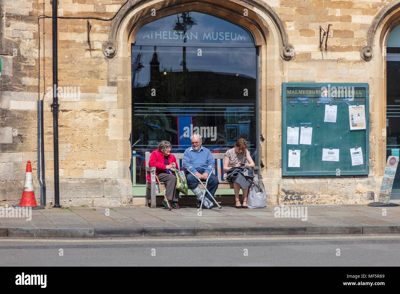 Les visiteurs de la ville de marché de Malmesbury, s'asseoir et se reposer sur des bancs à l'extérieur de l'hôtel de ville sur les Hayes, Wiltshire, Royaume-Uni Banque D'Images