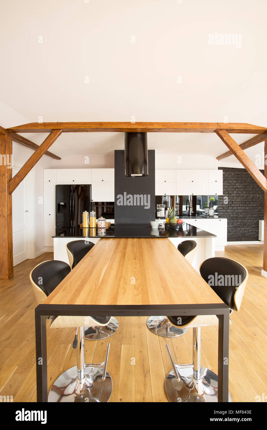 Tabourets De Bar en bois à table dans une spacieuse cuisine intérieur avec des meubles blancs et de comptoir noir Banque D'Images