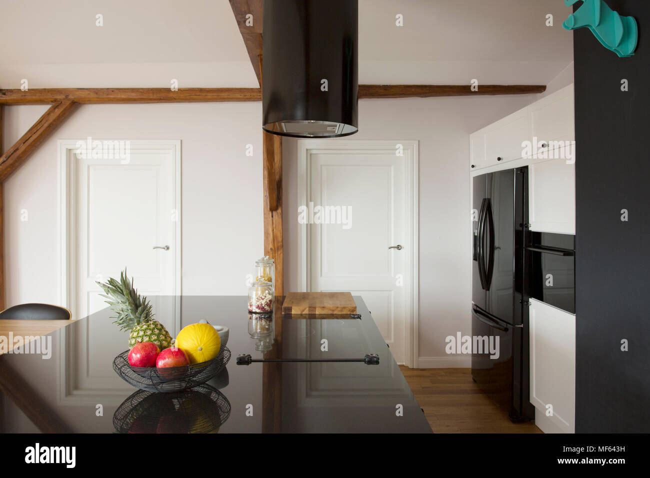 Fruits sur noir brillant sur le comptoir de cuisine île dans l'intérieur de la chambre avec portes blanches Banque D'Images