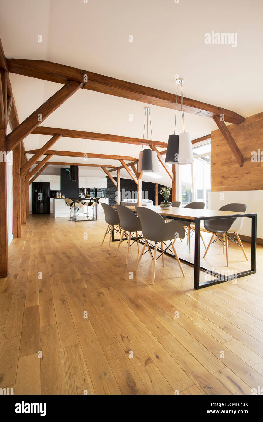 Table à manger en bois au-dessus des lampes et des chaises dans un espace libre intérieur avec cuisine dans l'arrière-plan Banque D'Images