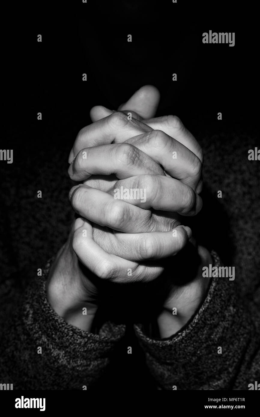 Gros plan des mains d'un jeune homme de race blanche, les mains jointes, en noir et blanc Banque D'Images