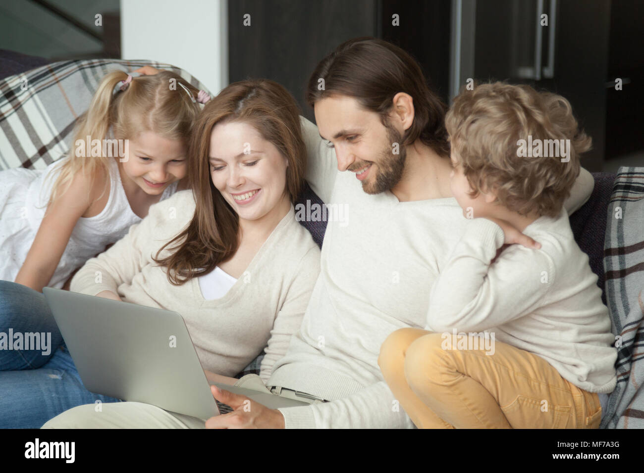 Smiling parents avec enfants s'amusant à l'aide de l'ordinateur portable sur canapé Banque D'Images