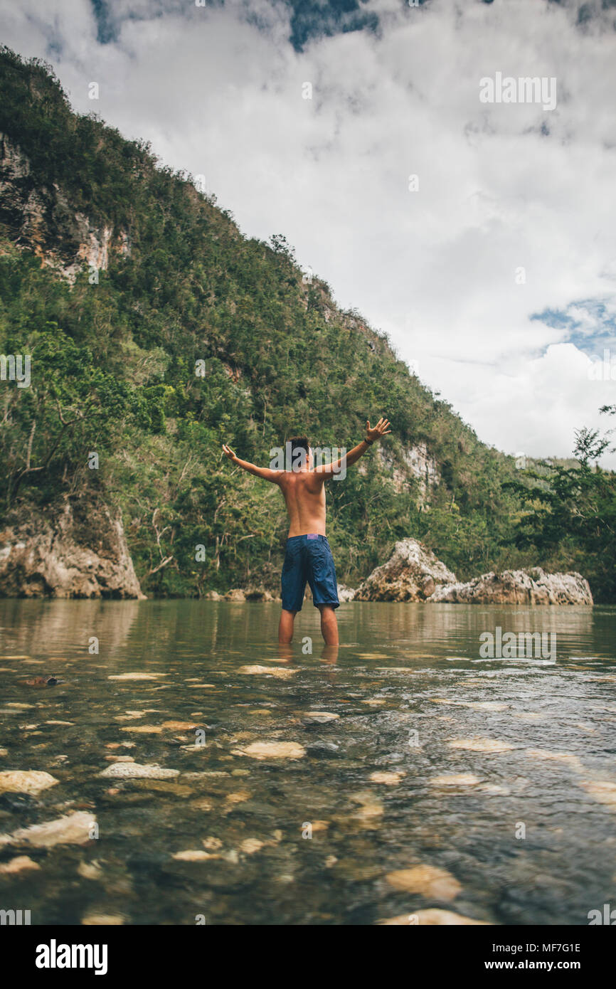 Cuba, Baracoa, jeune homme debout dans la rivière Yumurí, vue arrière Banque D'Images