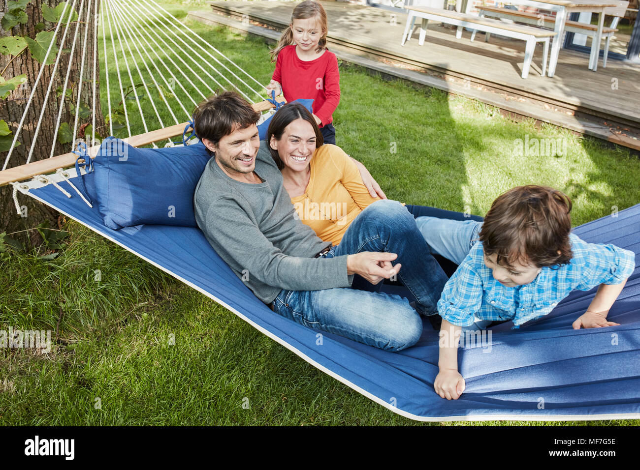 Happy Family playing in hammock dans jardin de leur maison Banque D'Images