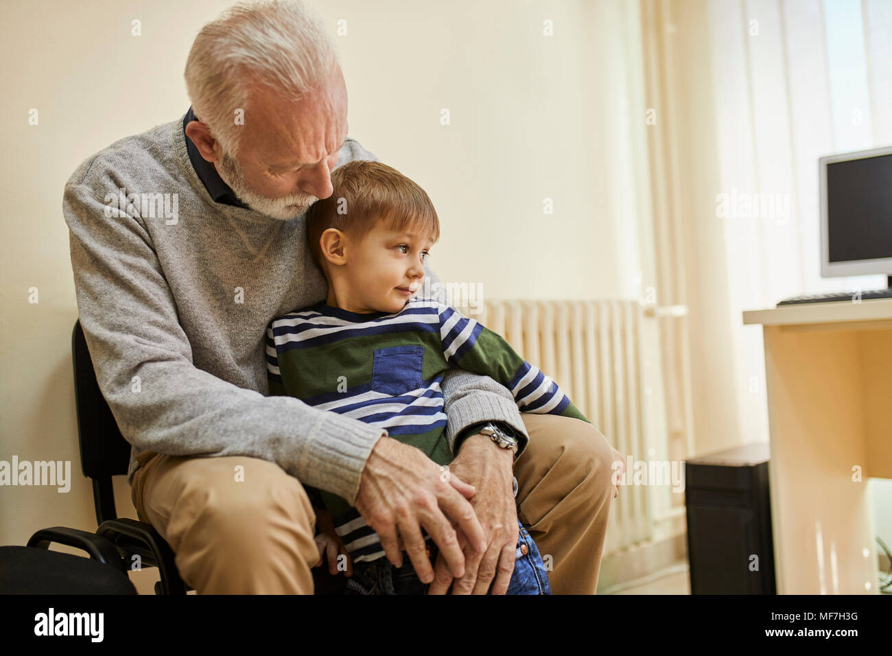 Garçon assis sur les genoux de grand-père dans la salle d'attente Banque D'Images
