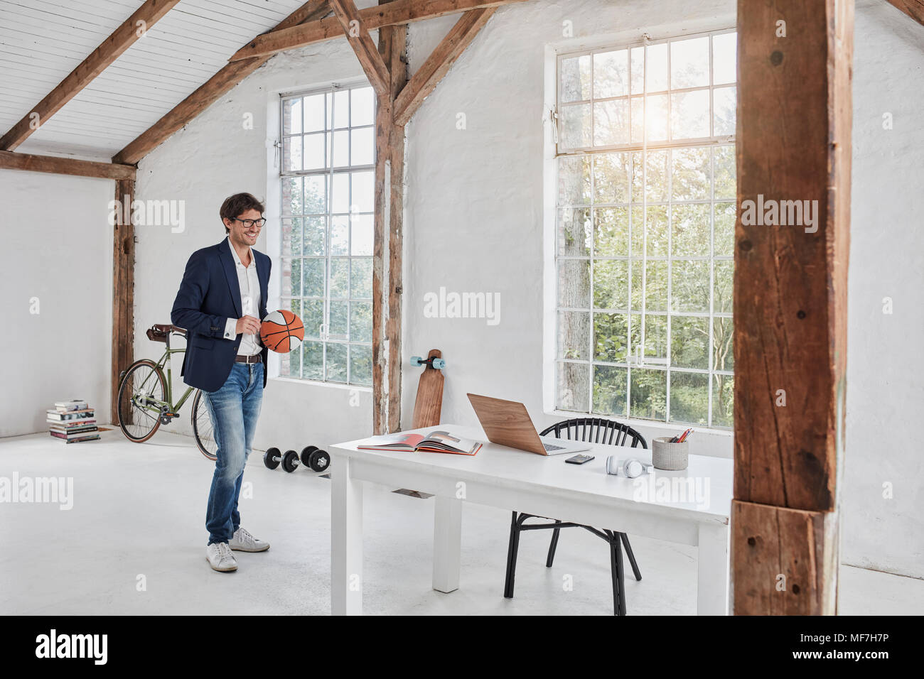 Smiling businessman with basketball dans penthouse Banque D'Images