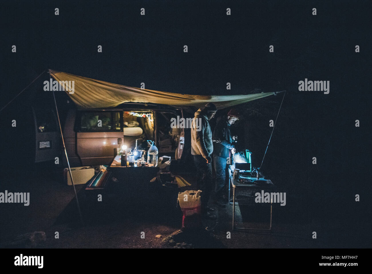 Le Canada, la Colombie-Britannique, deux hommes la cuisson sous bâche à minibus de nuit Banque D'Images
