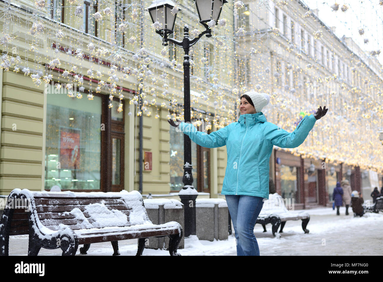 Femme positive étendit ses mains sur les côtés de la rue de la ville d'hiver Banque D'Images