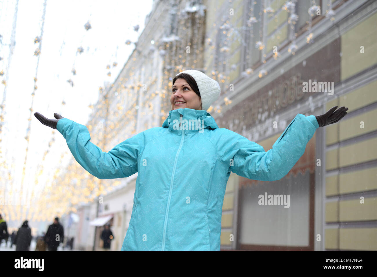 Femme positive étendit ses mains sur les côtés de la rue de la ville d'hiver Banque D'Images