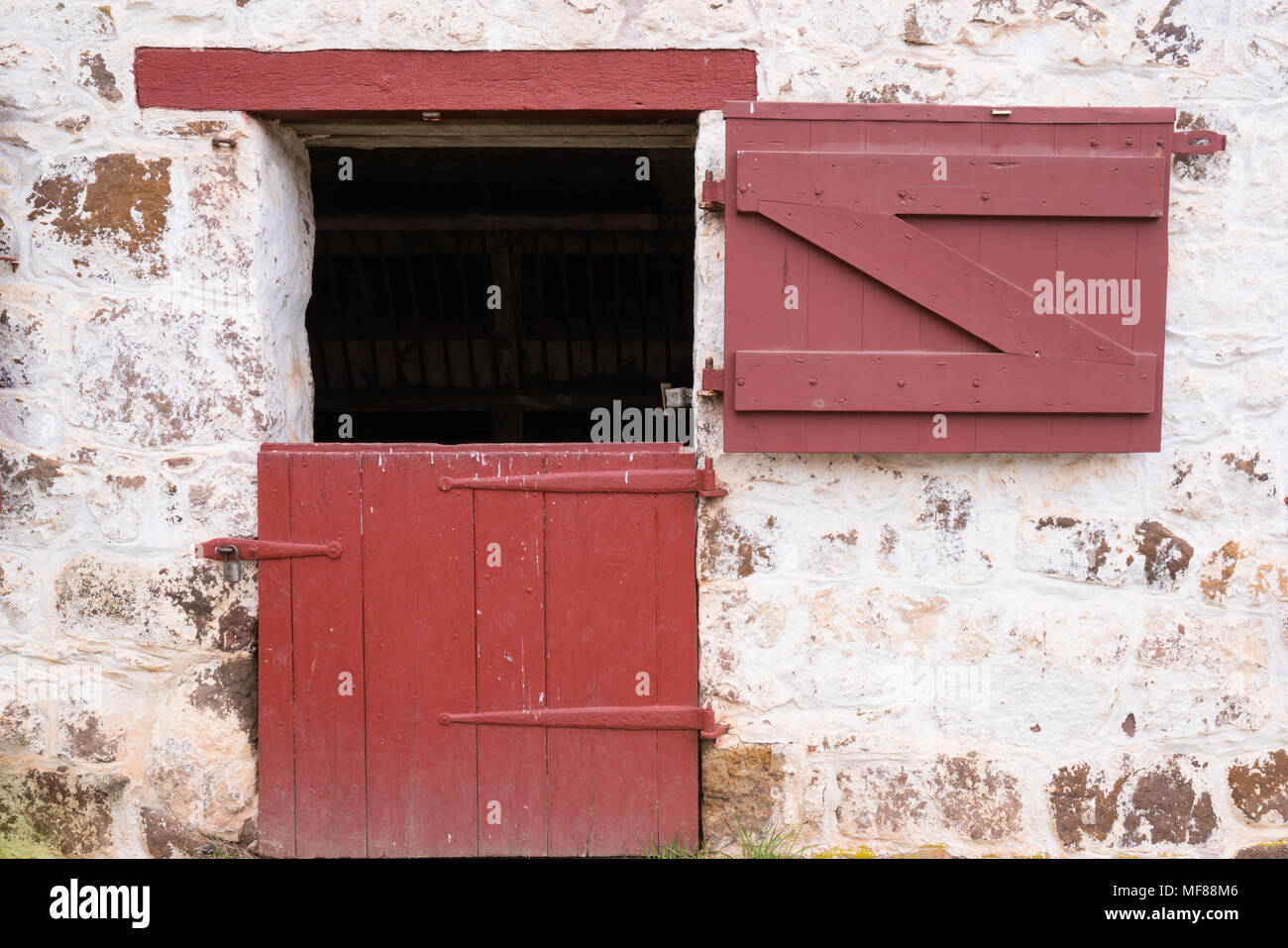Vieille porte rouge sur la grange en pierre blanchis Banque D'Images
