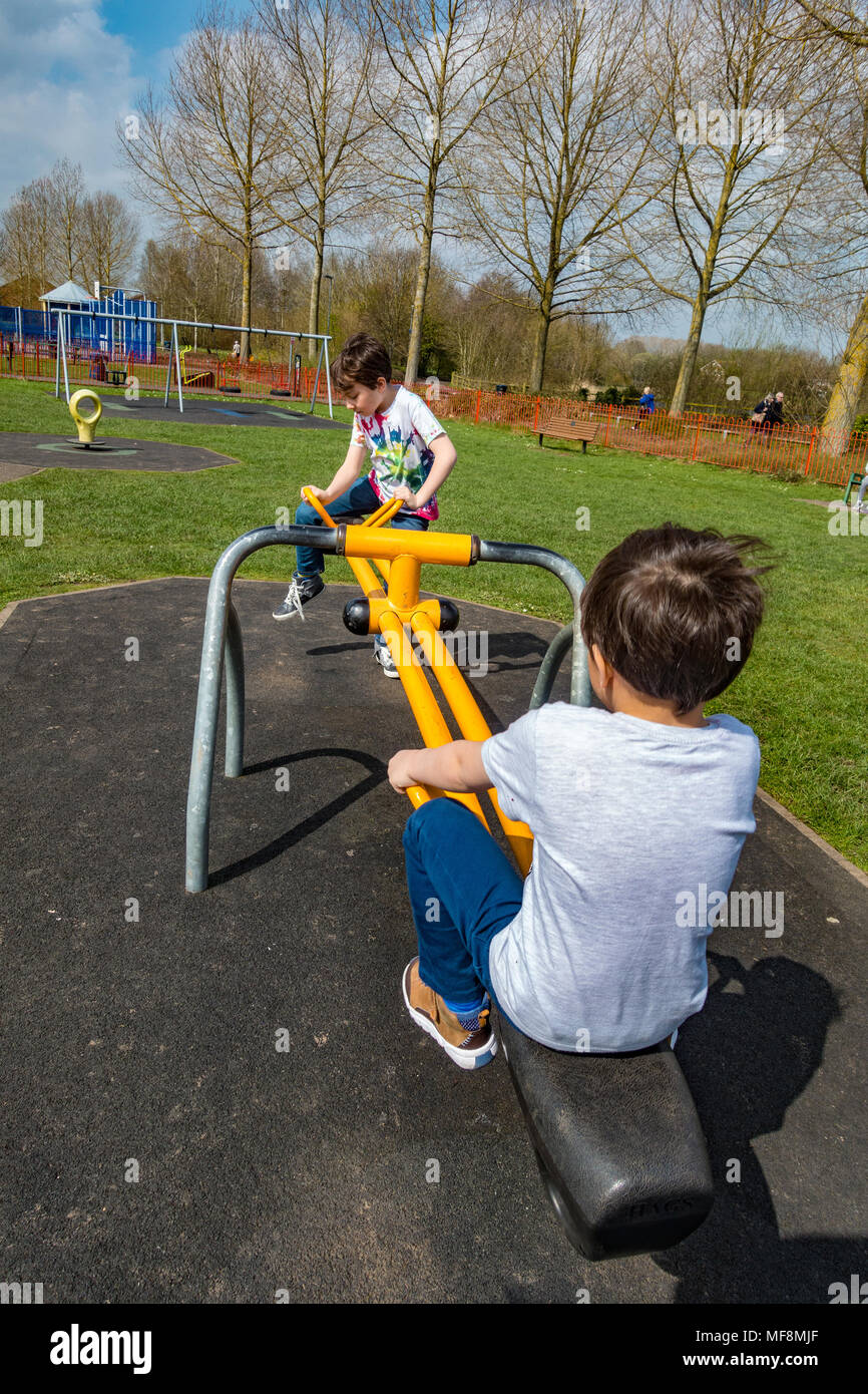Frères jouant sur une balançoire dans un aire de jeux pour enfants dans le village de tonne près de Wolverhampton. Banque D'Images