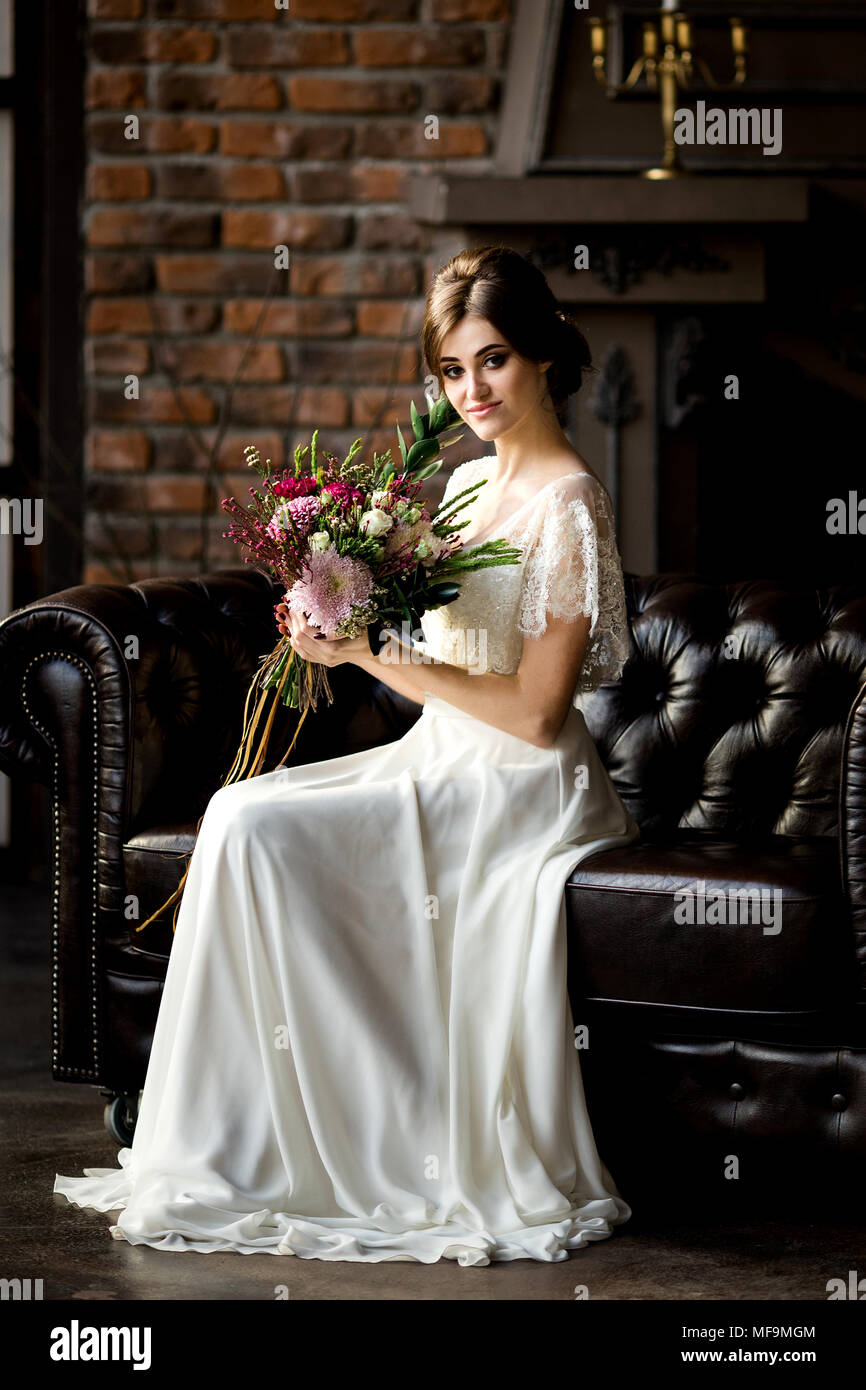 Belle robe de mariée assis sur une chaise à l'intérieur dans dark studio intérieur comme à la maison. Banque D'Images