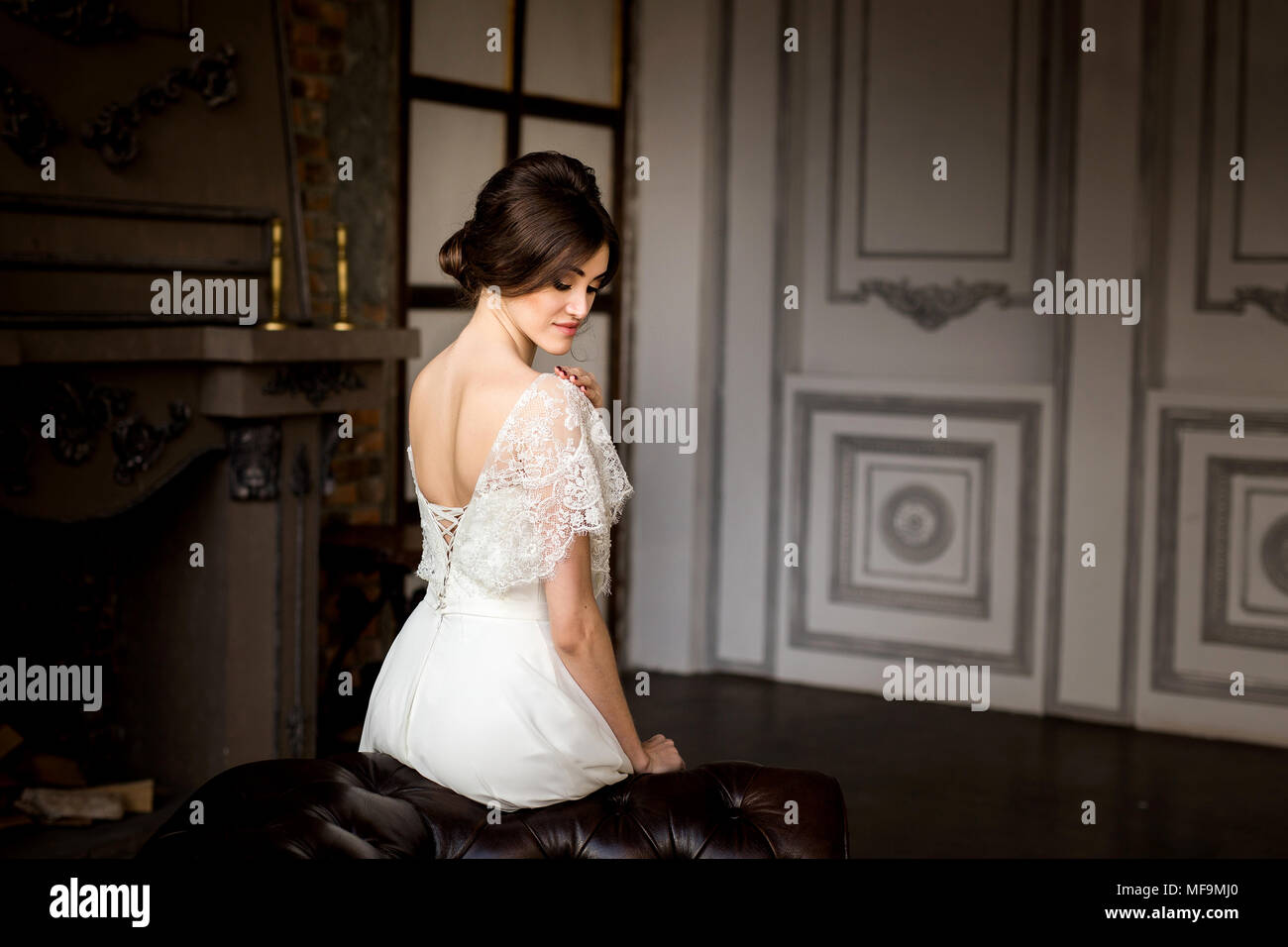 Belle robe de mariée assis sur une chaise à l'intérieur dans dark studio intérieur comme à la maison. Banque D'Images