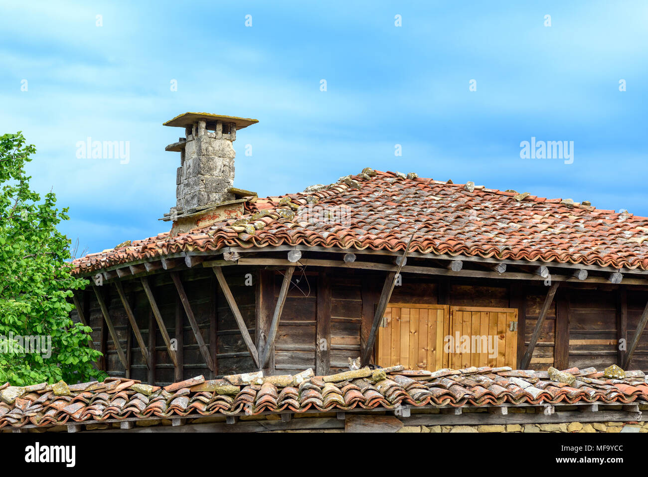 Zheravna, Bulgarie - Seule une authentique maison rustique en pierre et en bois avec portes fermées de volets en bois et toit de tuiles contre le ciel bleu Banque D'Images