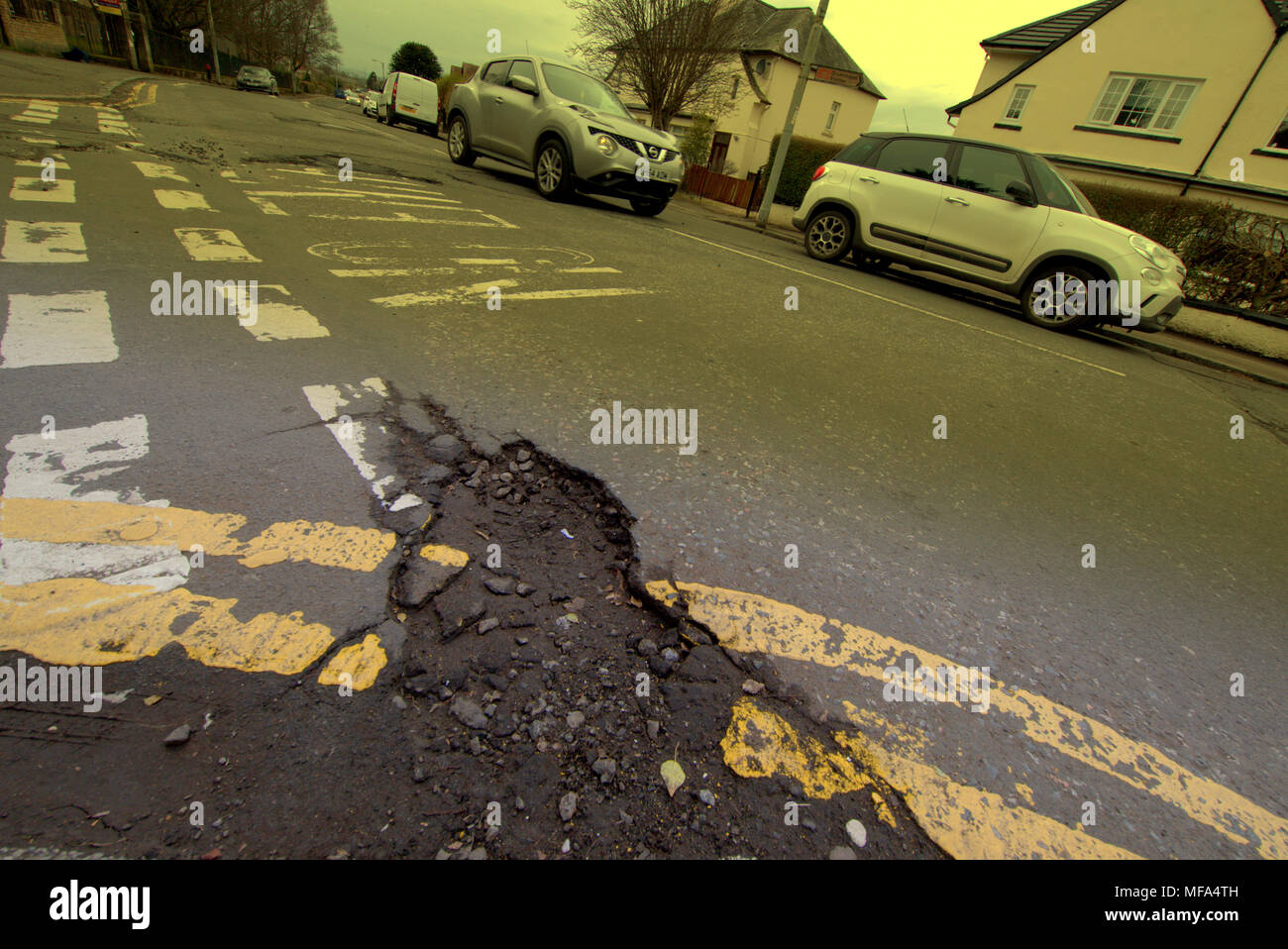 Route endommagée trous pot voiture voitures sur rue avec double yellow lines aucun marquage d'entrée Banque D'Images