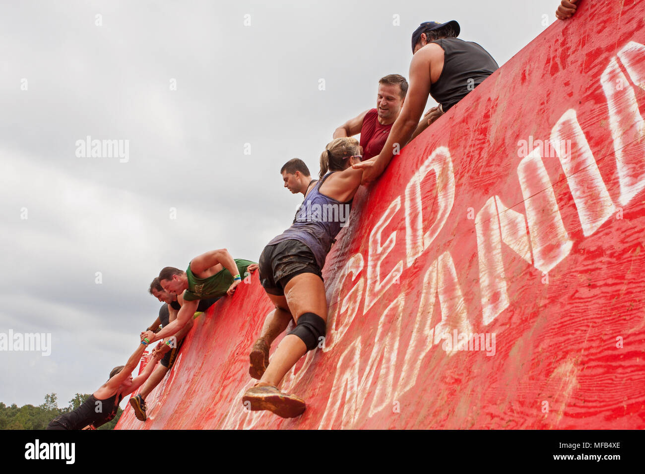 Les concurrents de la difficulté à grimper en haut d'un mur un peu l'aide des autres participants à l'événement robuste Maniac le 22 août 2015 à Conyers, GA. Banque D'Images