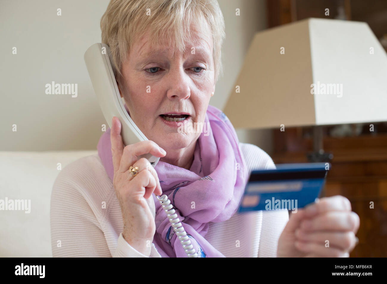 Senior Woman en donnant des détails de carte de crédit au téléphone Banque D'Images