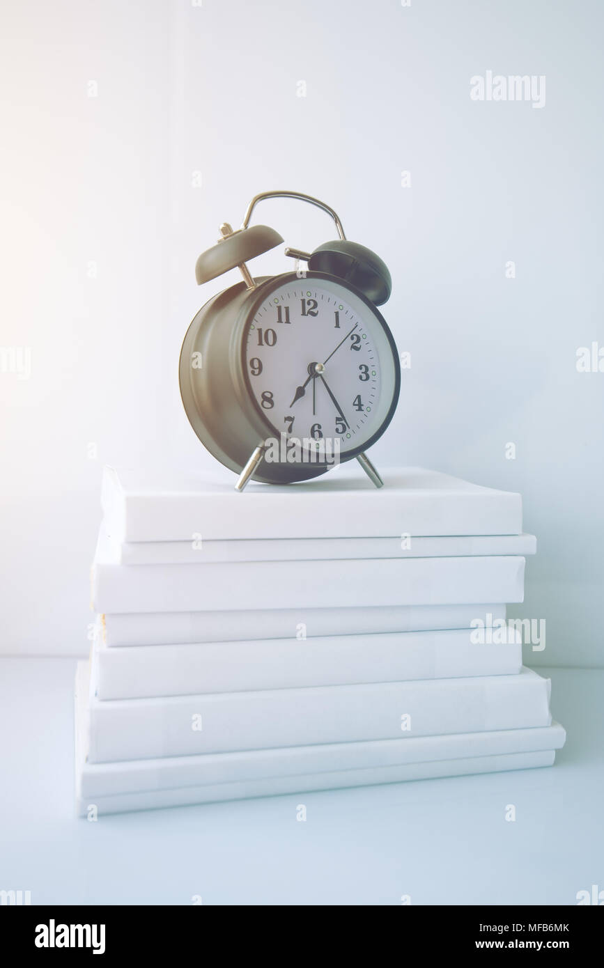 Le temps de service et d'étudier pour les examens. Vintage réveil sur le dessus de la pile de livres. Banque D'Images