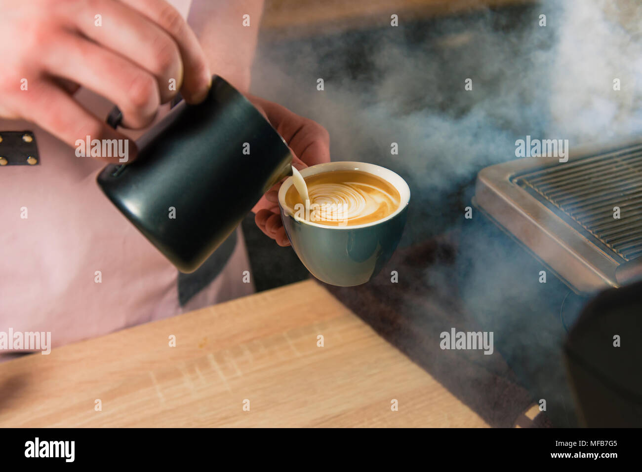 Faire un dessin avec une mousse de lait pichet pour tasse. Ajouter le lait au Barista espresso dans art façon. Banque D'Images