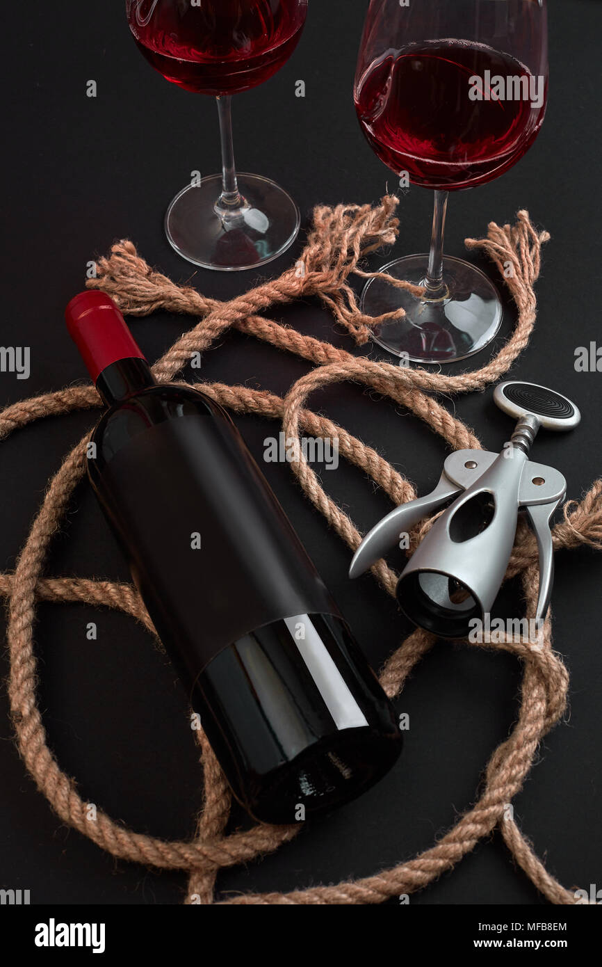 Bouteille de vin rouge, deux verres et corkscrew sur fond noir. Top View with copy space Banque D'Images