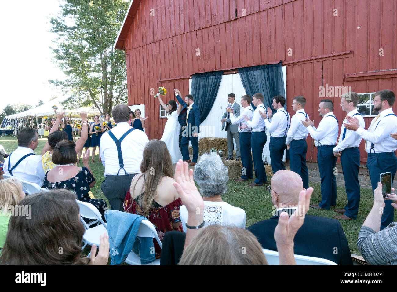 Heureux mariés lever les bras à la fin de la cérémonie de mariage dans un cadre rural avec une grange en toile de fond. IL USA ILLINOIS Champaign Banque D'Images