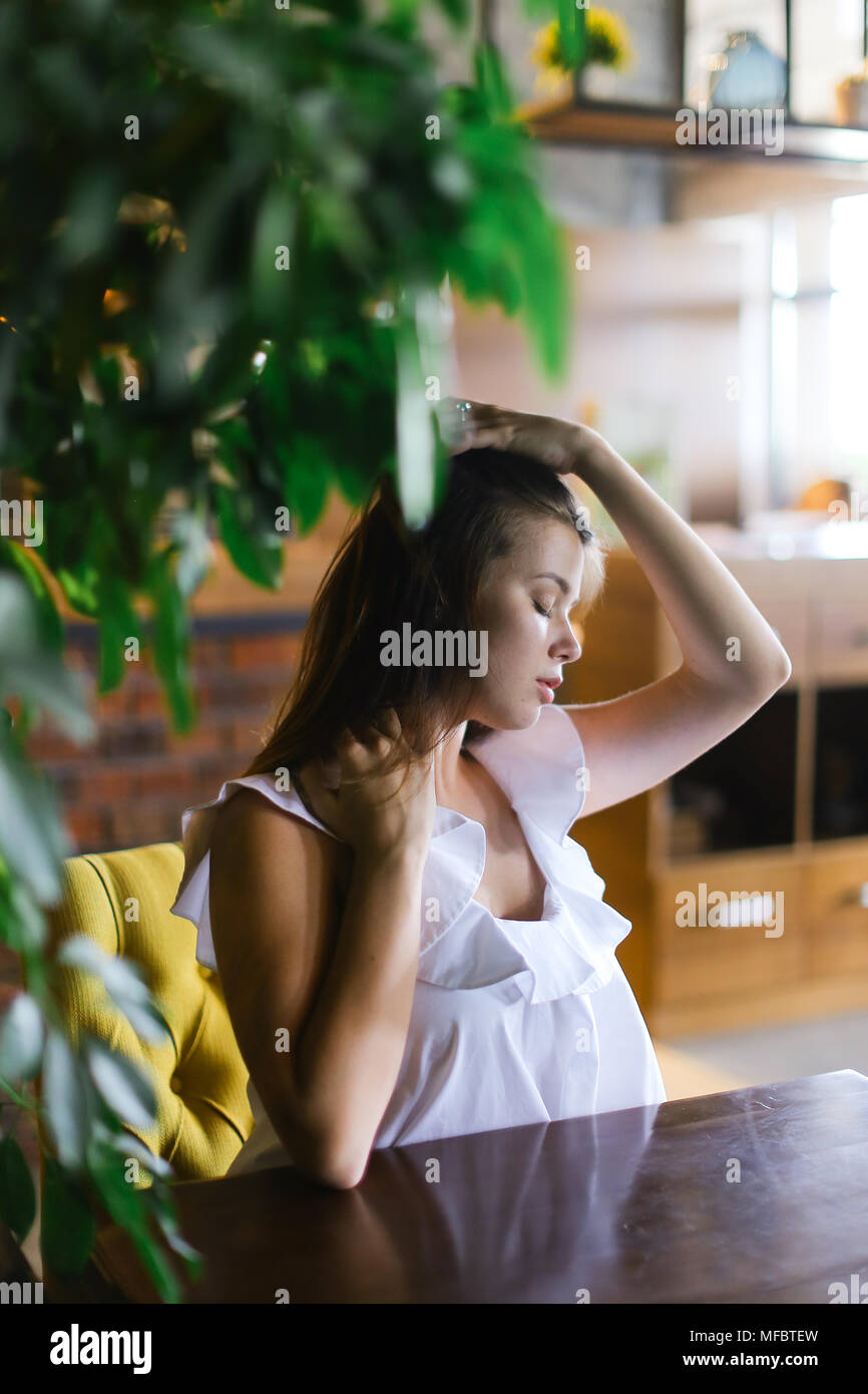 Fille avec main levée assis à table à côté de prix usine. Banque D'Images