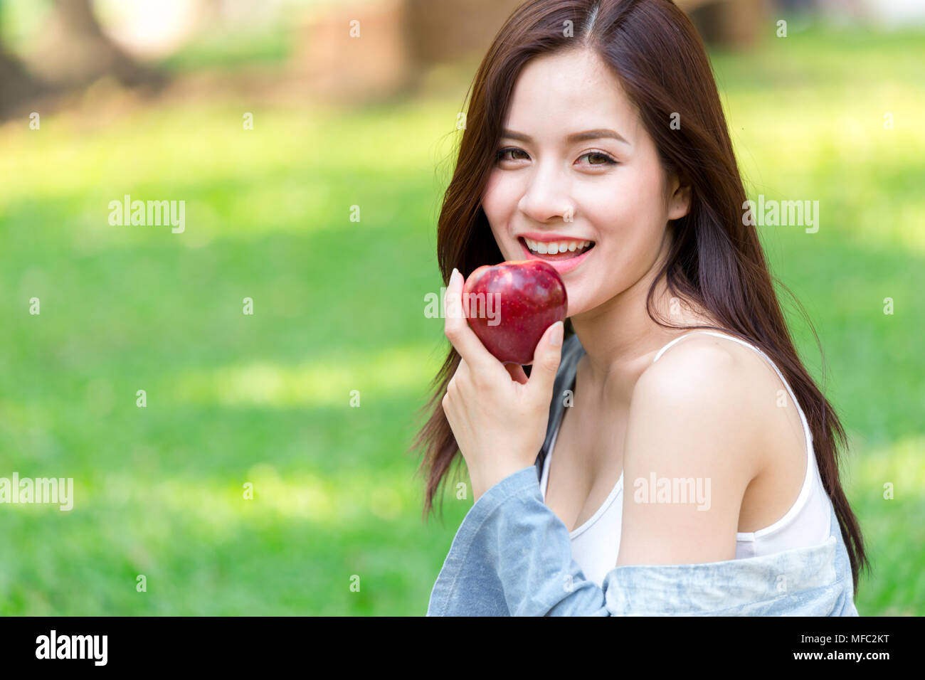 Asian young Beautiful Girl with red apple sur un fond de nature vert Banque D'Images