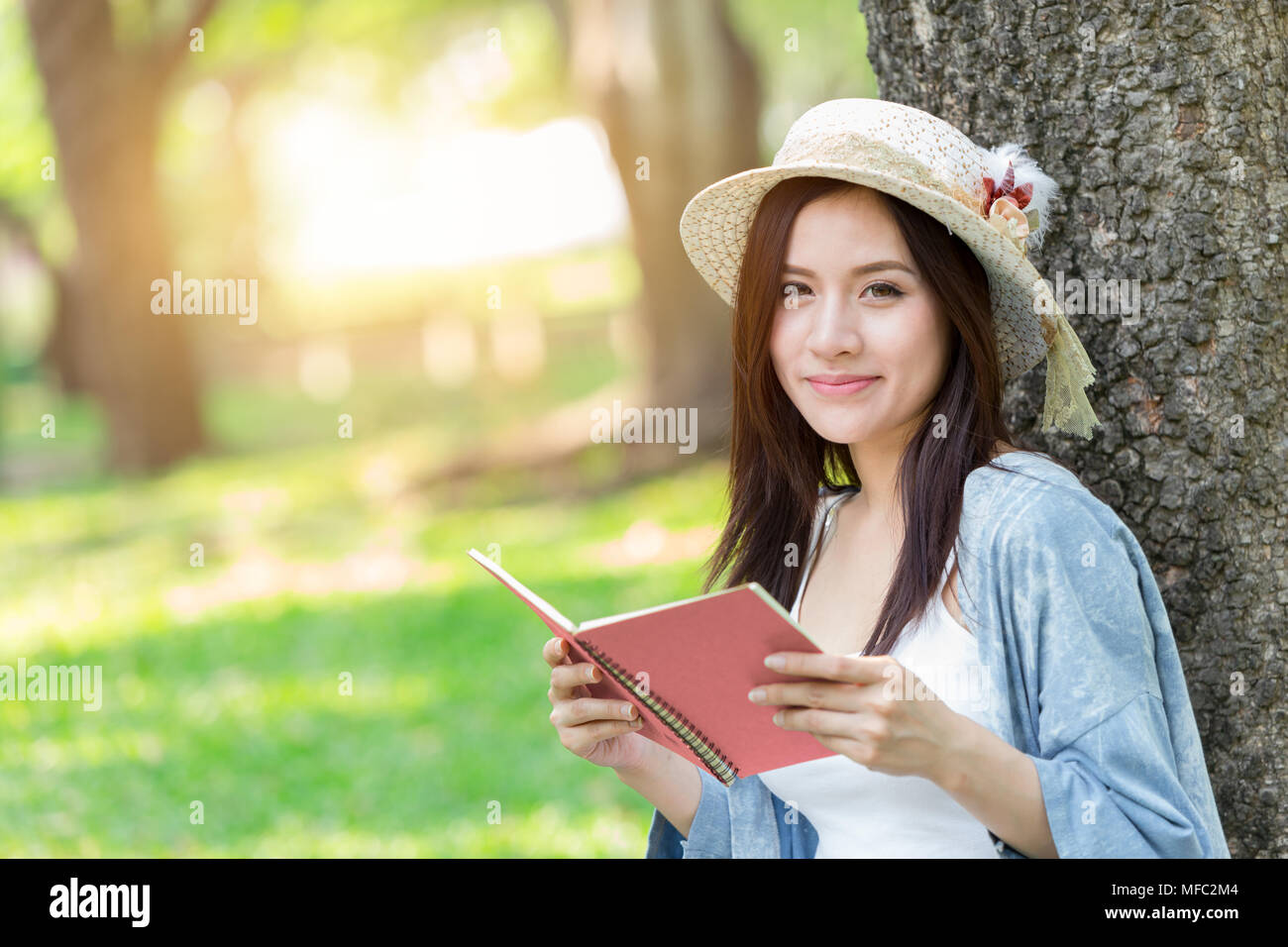 Belle asiatique femme lecture livre rose dans le parc ou de journal de la mémoire d'amour Banque D'Images