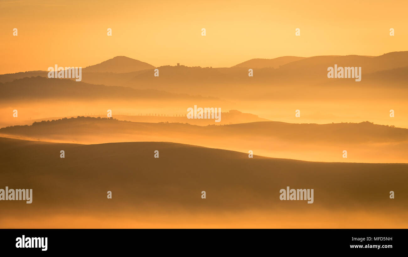 Sunrise pittoresque en Toscane, Italie. Matin brumeux avec des formes de brouillard, comme par magie, les collines et les vallées de ce magnifique lieu touristique à San Quirico d'Orcia région. Image horizontale Banque D'Images