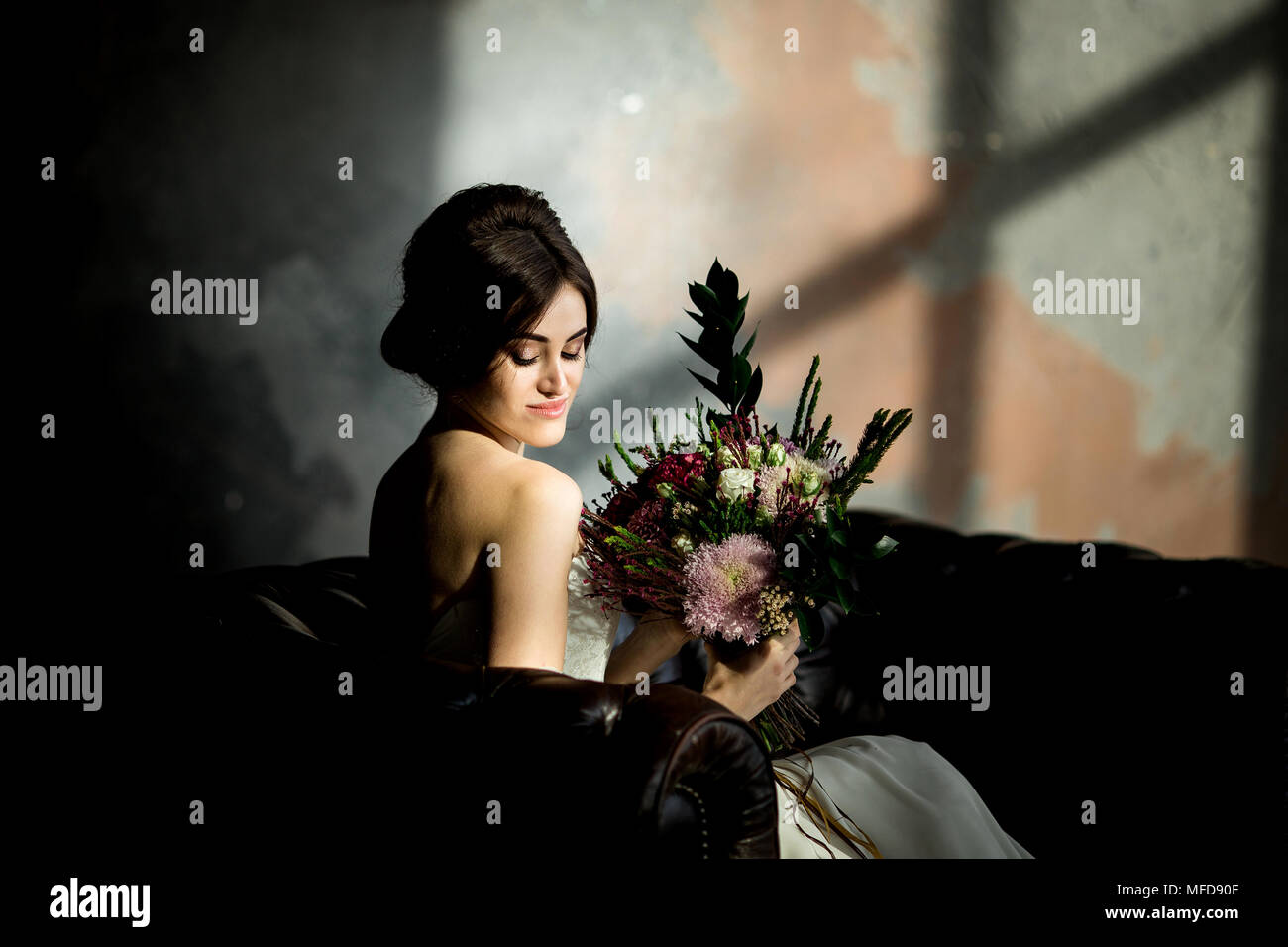 Belle robe de mariée assis sur une chaise à l'intérieur dans dark studio intérieur comme à la maison. Banque D'Images