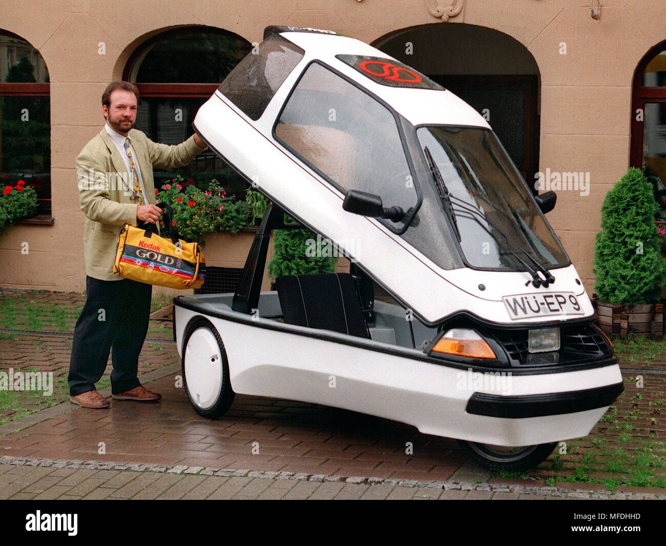 Le partenaire de gestion de Ville Com Elektromobile GmbH (au près de Würzburg), Karl Nestmeier, met un sac dans le véhicule sur 12.8.1996 lors de la présentation de la monoplace, 'City-el'. La voiture électrique, qui a été fabriqué au Danemark à partir de 1987 jusqu'au printemps 1995, est maintenant d'être produite en Allemagne. Cette année, près de 300 pièces de la monoplace sera construit à trois roues, il sera facturé à un socket et a une autonomie de 50 kilomètres. La voiture coûte environ 12 000 points. La société de projet Ville Com au Danemark a déposé son bilan. Dans le monde d'utilisation | Banque D'Images