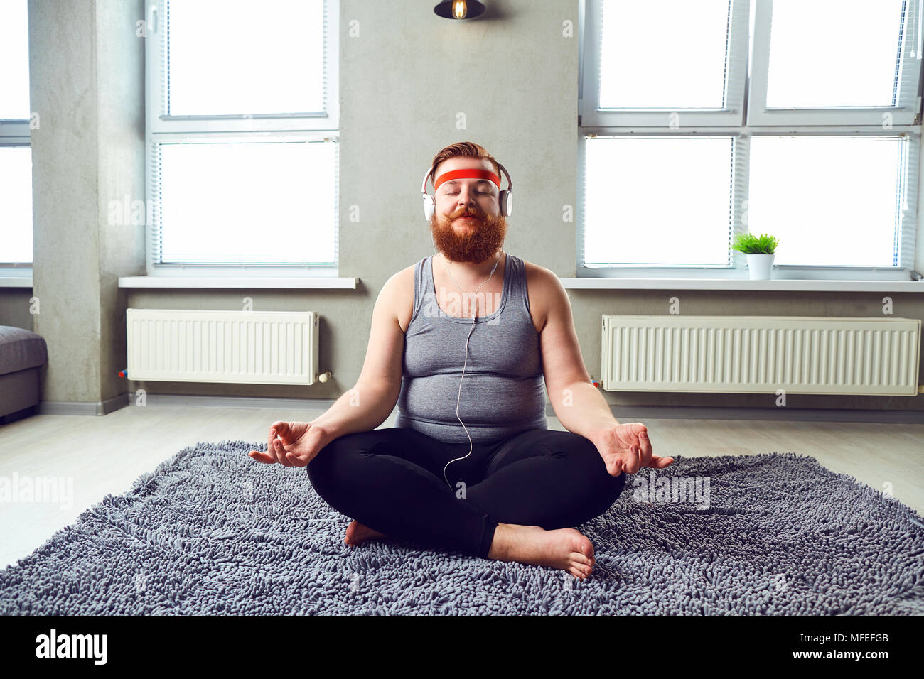 Un drôle de gros barbu dans les casques n'yoga. Banque D'Images