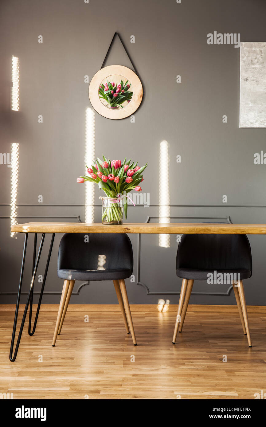 Chaises gris à table en bois avec des fleurs à l'intérieur salle à manger au décor sur le mur Banque D'Images