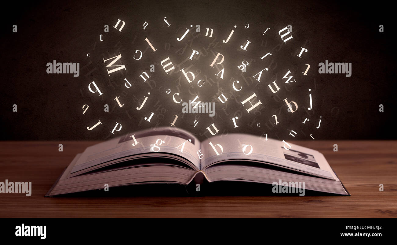 Lettres alphabet blanc brillant qui sort d'un livre ouvert Photo Stock