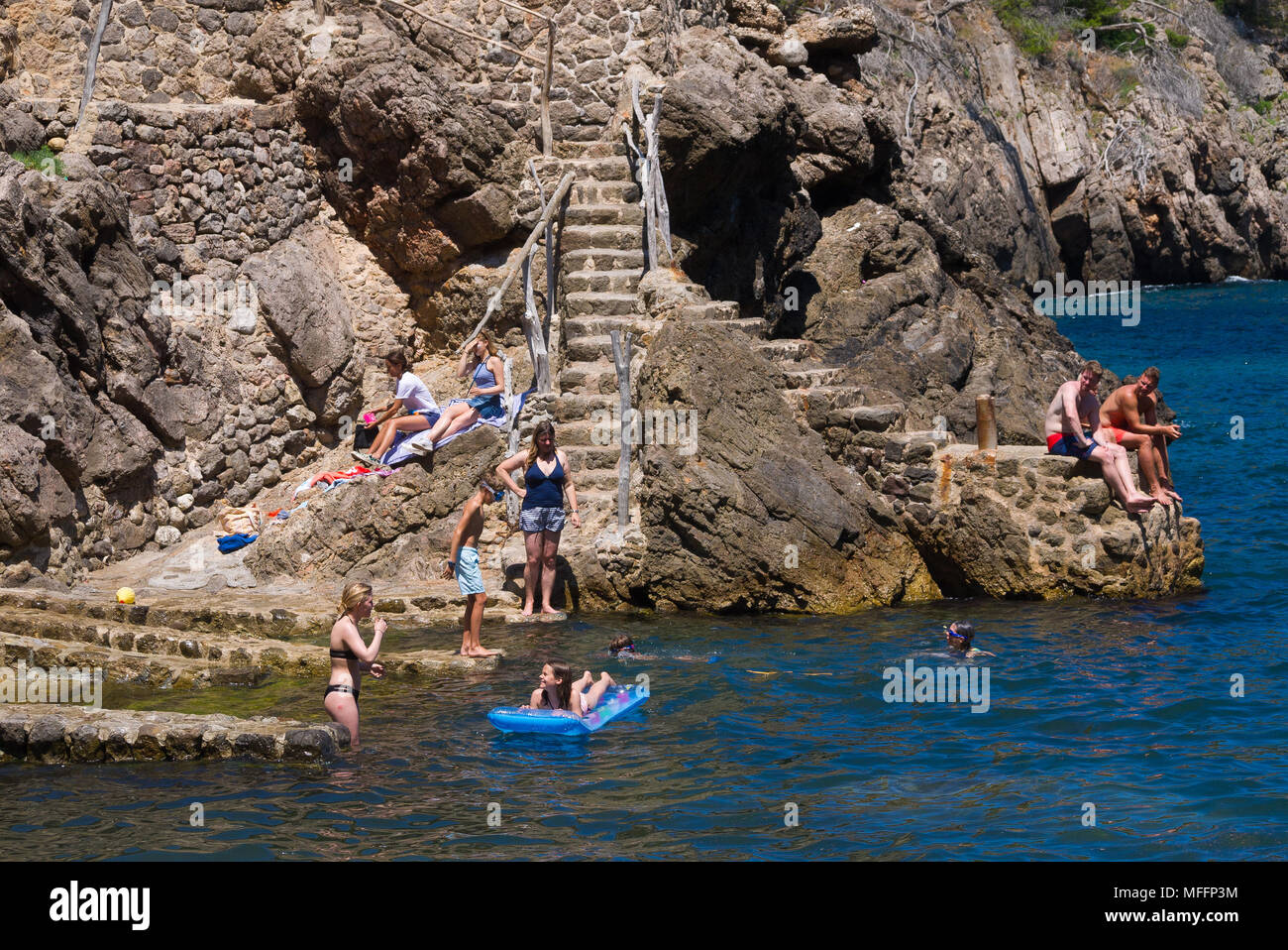 Jouissent d'une chaude journée ensoleillée au bord de l'eau à Cala Deia, Mallorca, Espagne. Banque D'Images