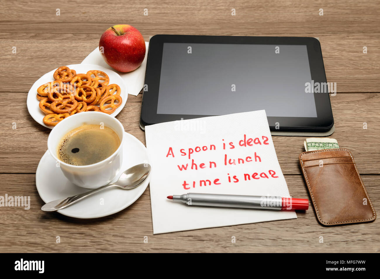 Message de l'écriture de serviette sur proverbe table en bois avec du café, de la nourriture et tablet PC une cuillère est cher quand l'heure du déjeuner est près de Banque D'Images